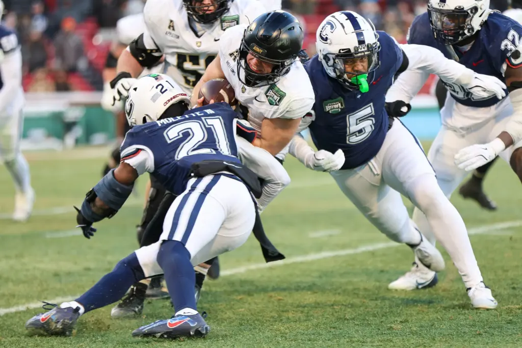 Army's Cale Hellums is tackled by UConn's Lee Molette III and Aaron Key during the Fenway Bowl at Fenway Park in Boston on Saturday, Dec. 27, 2025.
