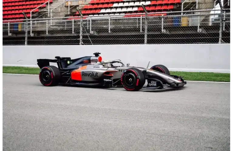 Formula 1 Audi, testing at Barcelona on track with red and gray livery, featuring sponsor logos like Revolut.