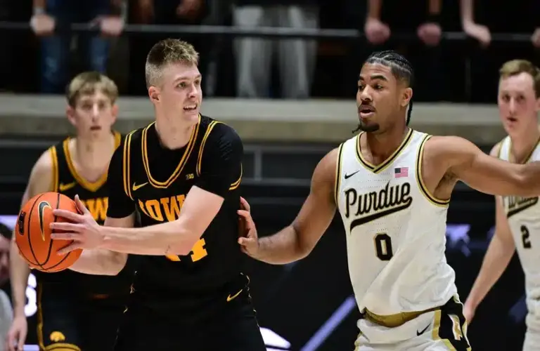 Purdue player CJ Cox guards an Iowa player.