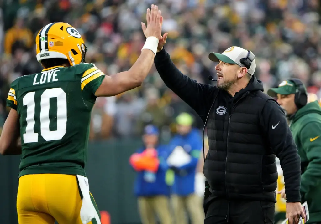 Packers quarterback Jordan Love high-fives coach Matt LaFleur at Lambeau Field; Love has faced heavy pressure behind the Packers offensive line