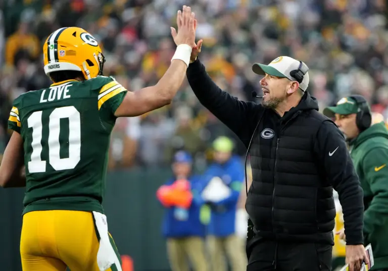 Packers quarterback Jordan Love high-fives coach Matt LaFleur at Lambeau Field; Love has faced heavy pressure behind the Packers offensive line