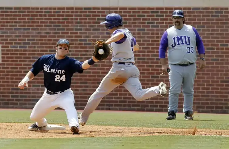 Jun 5, 2011; Chapel Hill, NC, USA; James Madison University outfielder Cole McInturff (4) beats the play by Maine first baseman Justin Leisenheimer (24) as JMU assistant coach Jason Middleton (33) looks on at the Chapel Hill regional of the 2011 NCAA baseball tournament at Boshamer Stadium.