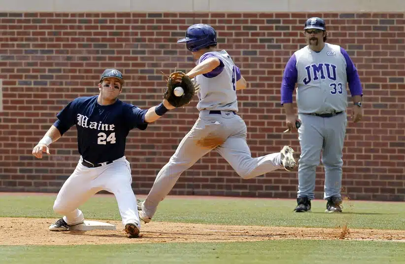 Jun 5, 2011; Chapel Hill, NC, USA; James Madison University outfielder Cole McInturff (4) beats the play by Maine first baseman Justin Leisenheimer (24) as JMU assistant coach Jason Middleton (33) looks on at the Chapel Hill regional of the 2011 NCAA baseball tournament at Boshamer Stadium.