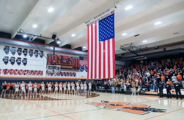A giant American flag is unfurled from the ceiling during the national anthem before the start of a high school basketball game between the Washington Panthers and Morton Potters on Tuesday, February 10, 2026 in Washington. The Panthers defeated the Potters 57-37 for the Mid-Illini Conference championship.
