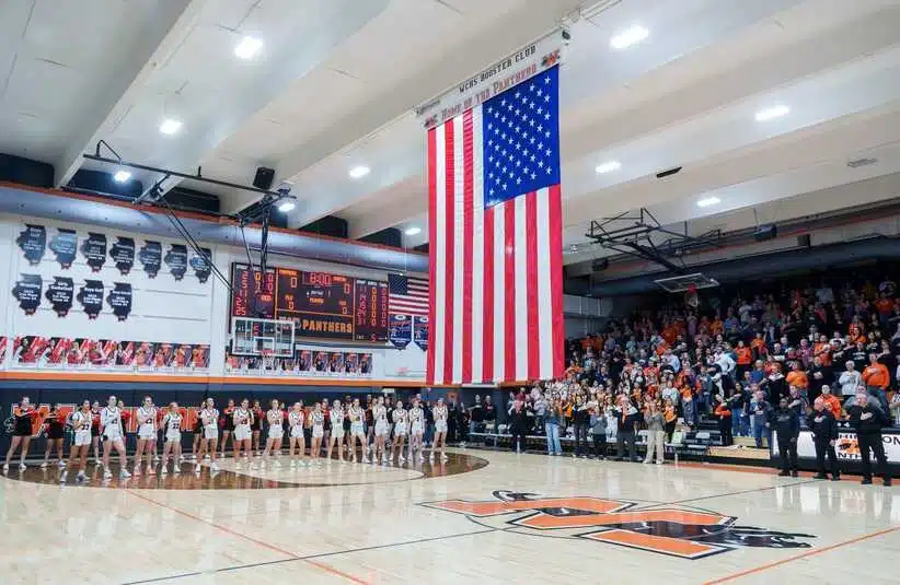 A giant American flag is unfurled from the ceiling during the national anthem before the start of a high school basketball game between the Washington Panthers and Morton Potters on Tuesday, February 10, 2026 in Washington. The Panthers defeated the Potters 57-37 for the Mid-Illini Conference championship.