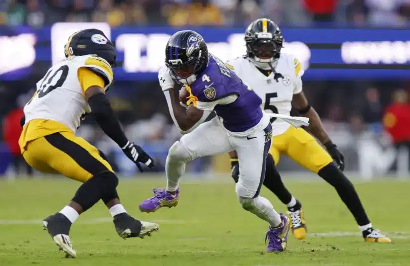 Baltimore Ravens wide receiver Zay Flowers (4) runs with the ball after making a catch in an NFL game.