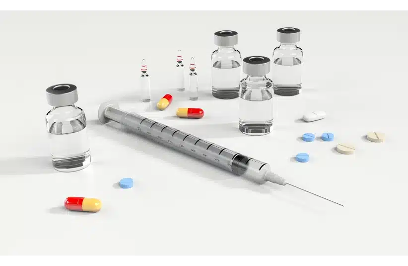 Syringe and various medications, including capsules, tablets, and vials, are arranged on a plain surface, conveying a medical theme. WADA responds to rumors of HA use among male ski jumpers at the 2026 Winter Olympics.