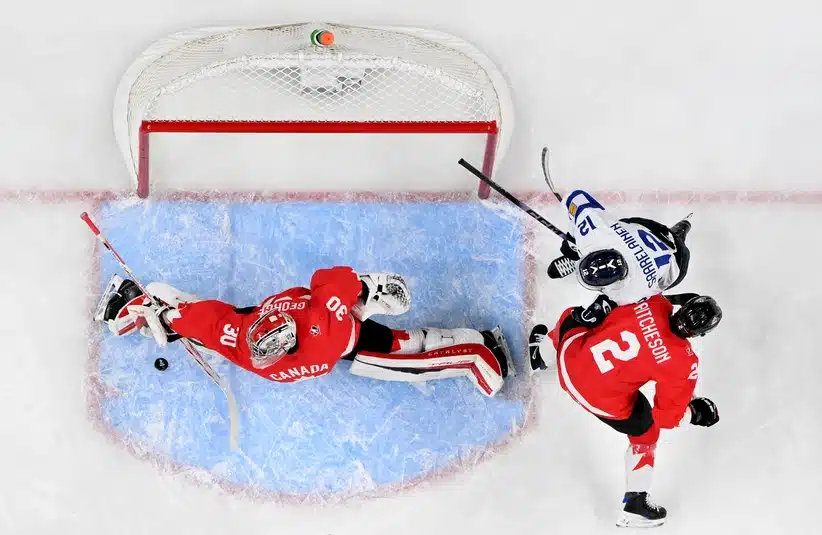 Jan 5, 2026; St. Paul, Minnesota, USA; Canada goalie Carter George (30) makes a save as defensemen Kashawn Aitcheson (2) and Finland forward Roope Vesterinen (12) battle for position during the third period in the third place game of the 2026 IIHF World Junior Championship ice hockey tournament at Grand Casino Arena.