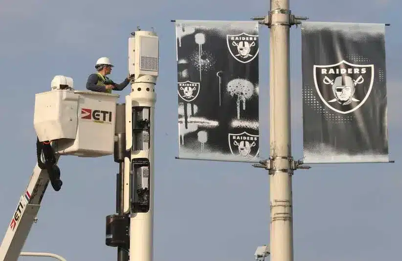 Workers prepare for the upcoming 2021 NFL Draft with a hanging Raiders Banner