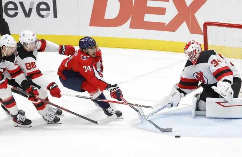 Washington Capitals center Justin Sourdif (34) controls the puck between New Jersey Devils center Jack Hughes (86)