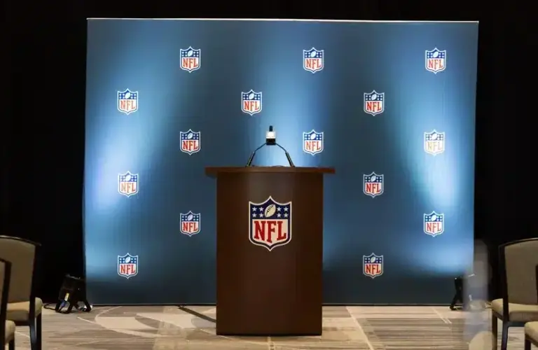 Detailed view of the NFL shield logo on a lectern in a press conference room.