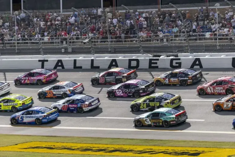 Oct 19, 2025; Talladega, Alabama, USA; Cars race by Talladega signage during stage one of the YellaWood 500 at Talladega Superspeedway.