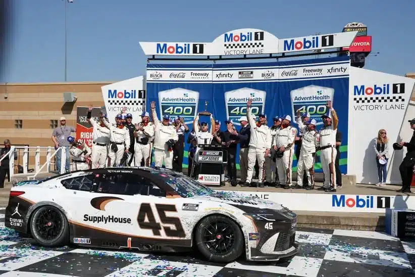 Apr 19, 2026; Kansas City, Kansas, USA; NASCAR Cup Series driver Tyler Reddick (45) and the rest of the team celebrate winning the AdventHealth 400 at Kansas Speedway.